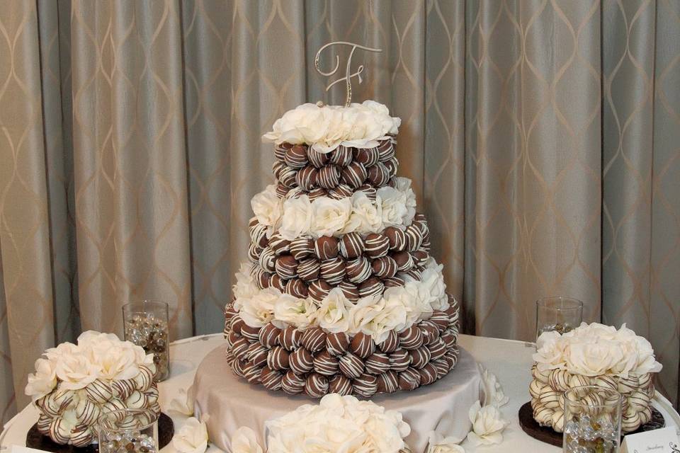 3 tiered cake bite wedding cake with individual satellite cakes.  Silk flowers added to cakes.