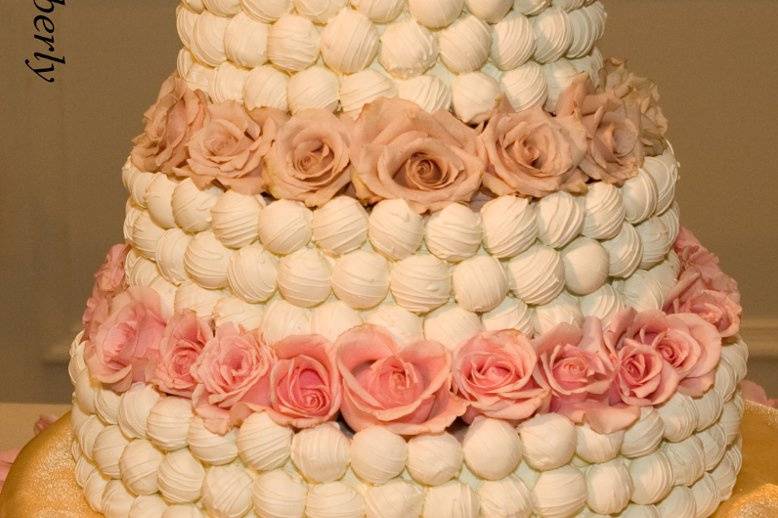 Cake bite wedding cake with fresh roses between tiers.
