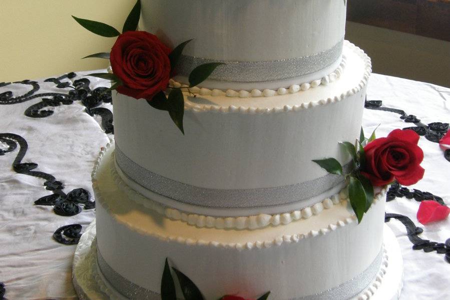 Tiered buttercream cake with fresh roses and ribbon.