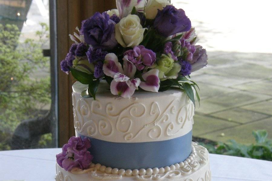 Tiered buttercream cake with satin ribbon and fondant pearls!  Fresh flowers are used for the topper.