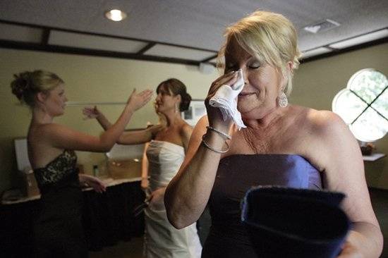 The mother of the bride wipes a tear while her daughters try to comfort each other prior to the ceremony.