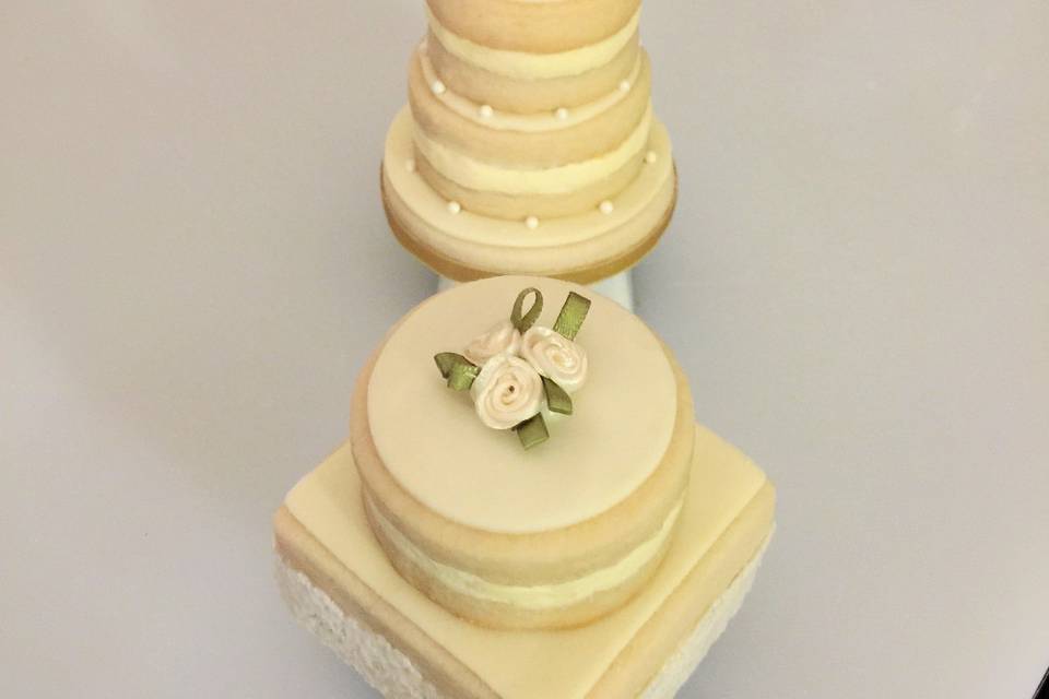 The perfect little wedding cake -
Shortbread cookies (our shortbread cookies are a bit sweeter and a bit moister than others) with layers of buttercream & fondant -
Cakes arrive individually boxed with a lovely hand tied satin ribbon and are suitable for service in or out of the clear box.
Contact us for personalized topper variety, availability and pricing.