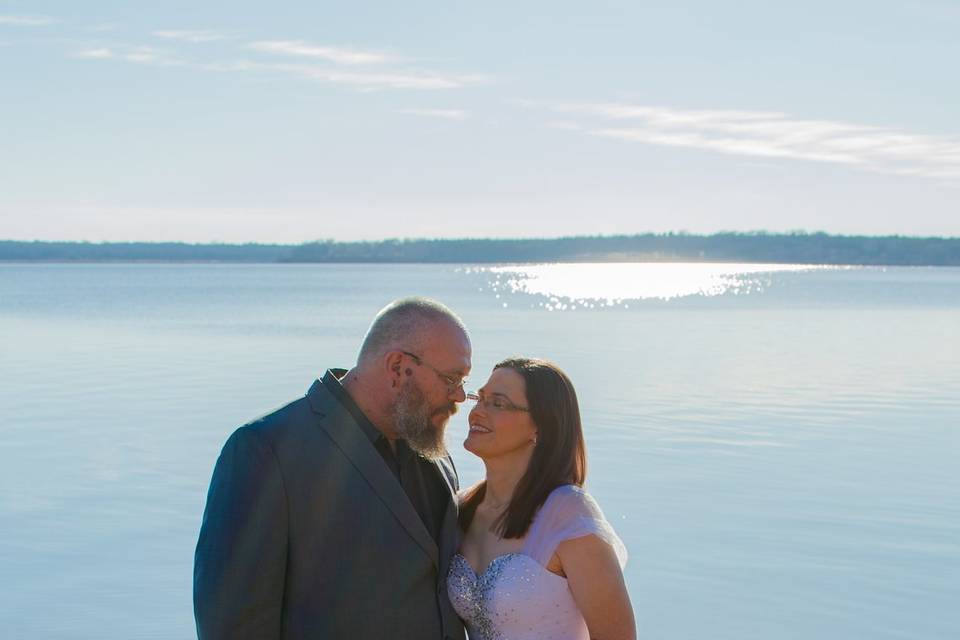 Couple stands by a blue lake