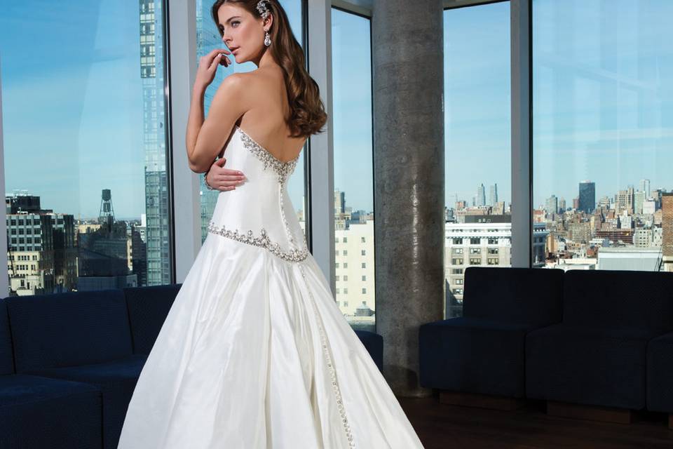 Style 9819 <br> The beaded spaghetti straps, geometric hand beading accents on the skirt, deep V front and back necklines and finished scalloped eyelash hem make this straight gown sleek and lavish.