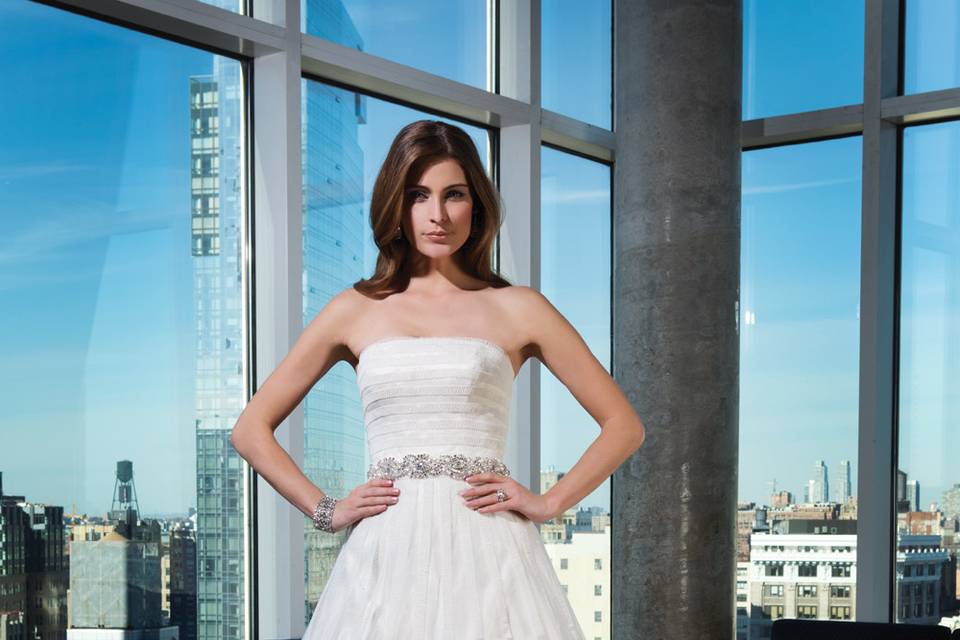 Style 9831 <br> Lace appliques draw the eye to the illusion long sleeves and V-neckline of this tulle fit and flare gown with point d'esprit underlay and a chapel length train.