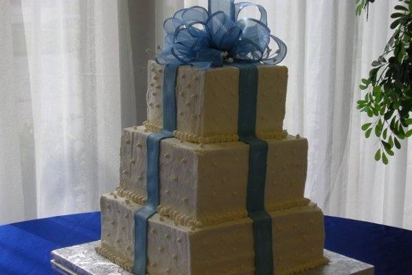 Butter cream covers this stack of boxes made of French vanilla cake.  Fondant ribbons adorn the sides in bright blue the color theme of this wedding.