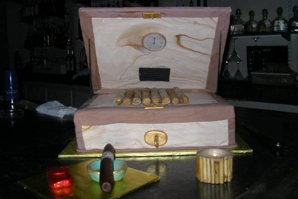 A cigar entusiasts delight was recreated in a fondant enrobed chocolate cake with fondant cigars, ash tray and lighter, for a grooms cake that made all the groomsmen smile.