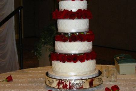 A red velvet cake covered with almond flavored fondant was made to serve 300 guests. The six tiers were separaed with beautiful red American Beauty roses placed in between each tier.