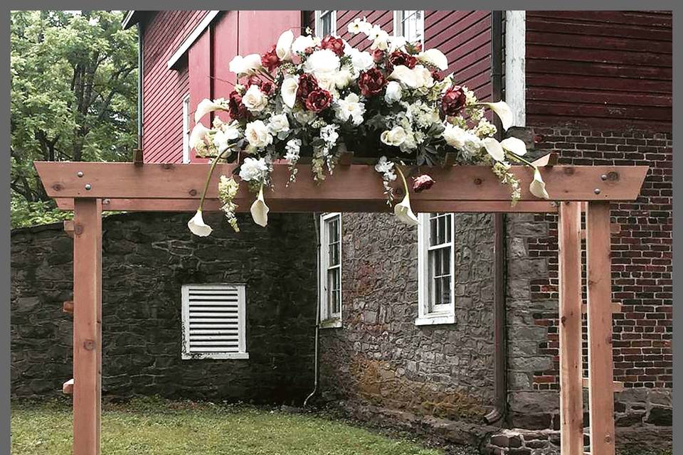This arch is portable and can be easily assembled by you or our staff. The flowers are interchangeable. Arch is pictured at Tinicum Barn in Bucks County, Pa. Rent this arch for $45.00.