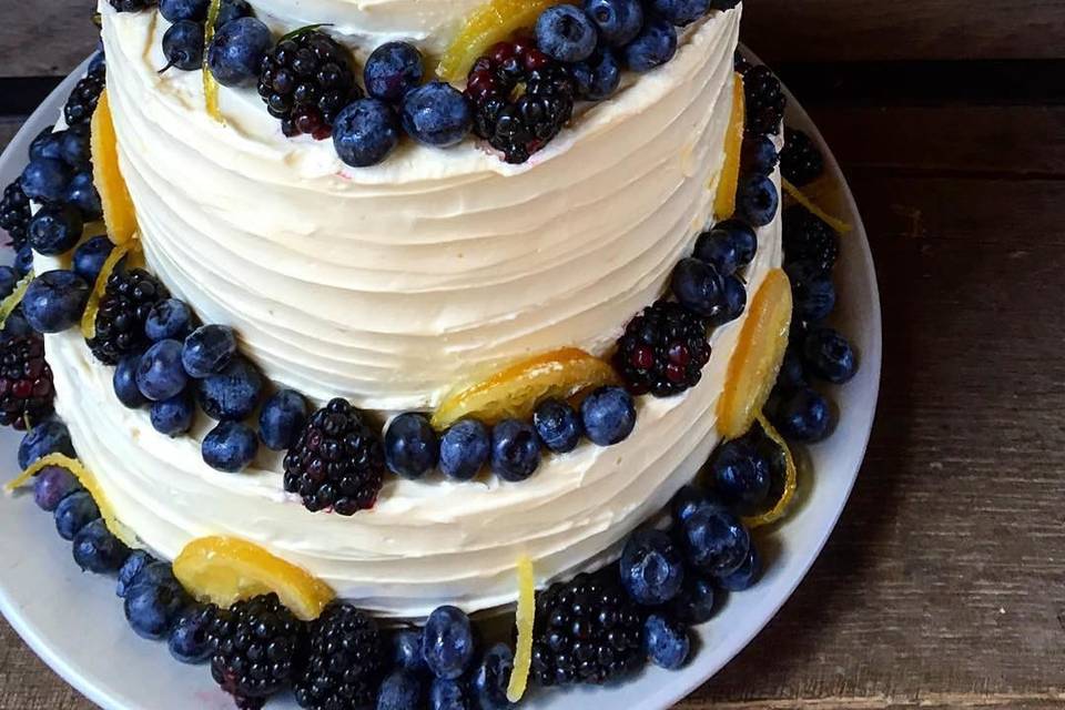Bride needed a special cake made with whole wheat flour.  Upstate Table delivered! This wedding cake was loaded with lots of lemon, perfect for a small summer wedding. Constructed with lemon curd between layers of lemony cake covered In a smooth lemony buttercream all topped with candied lemon, local blueberries and blackberries.