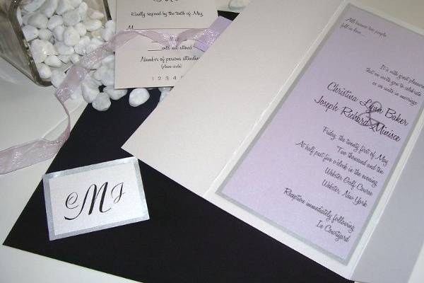 Lilac Love
This silver and purple invitation is nothing less than stunning! The invitation card will be printed on a gorgeous light purple metallic paper, bordered in silver metallic paper and adhered to a matching white metallic jacket. The jacket will be wrapped with a beautiful sheer purple ribbon with a tag displaying your monogram or wording of choice. Reply card and reception card can be secured inside jacket or fitted behind the ribbon.