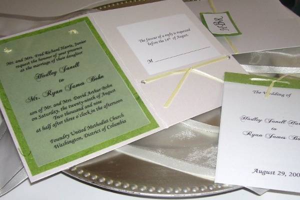 Meadow
Modern meets organic with this pocketfold invitation. The pocket is made with a thick white metallic paper. Inside is the invitation printed on vellum and attached with knots made of a pale yellow satin ribbon which is draped over a green handmade paper filled with silk. The side pocket is made with eyelets and tied with the same light yellow satin ribbon. This invitation set includes a 4 page information booklet.