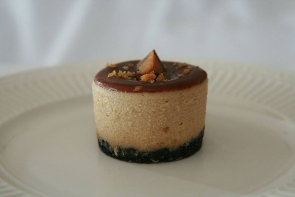 Peanut Butter Cup Cheesecake - Rich and Creamy Peanut Butter Cheesecake filled with peanut butter cup pieces, topped off with a chocolate Ganache and finished with an Oreo and Peanut crust.