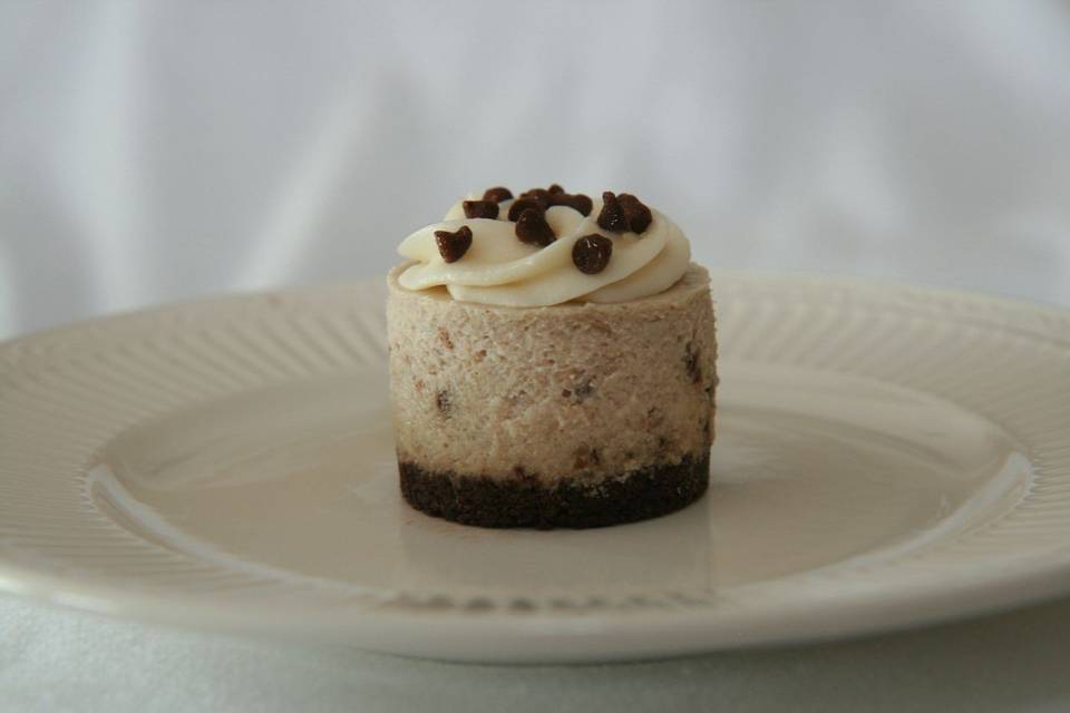 Banana Walnut Chocolate Chip Cheesecake - Creamy Banana Cheesecake with walnut pieces and mini chocolate chip pieces, topped with vanilla butter cream and finished with a double chocolate crust