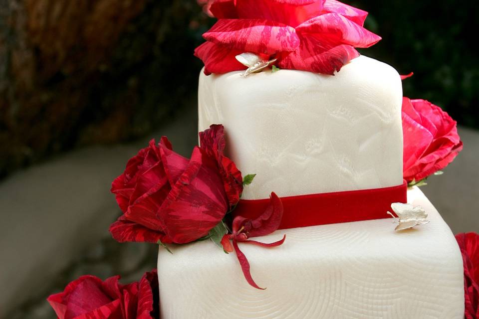 Wedding cake with red flowers and ribbons