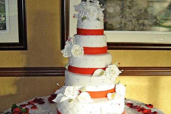 WHITE ROUND CAKE WITH RED RIBBON AND WHITE FLOWERS