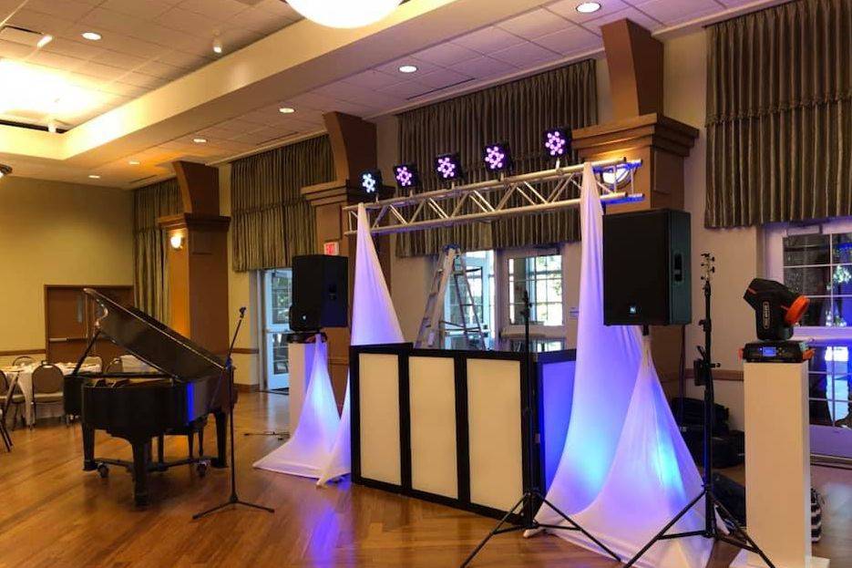 DJ booth setup in front of a piano