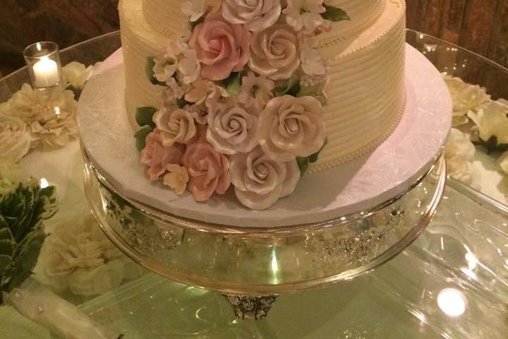 Buttercream three tier wedding cake adorned with handmade floral arrangement.