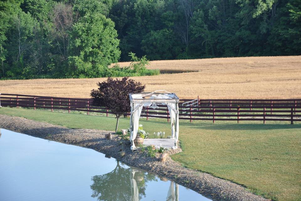 Our pergola sits on the edge of our pond graced with fabric and a chandelier.  Beautiful wine barrels filled with climbing hydrangea sit at the back of the pergola.  The view in any direction is stunning.  To the North its the wheat fields, to the South the pond, the West is our forest and to the East is the barn.