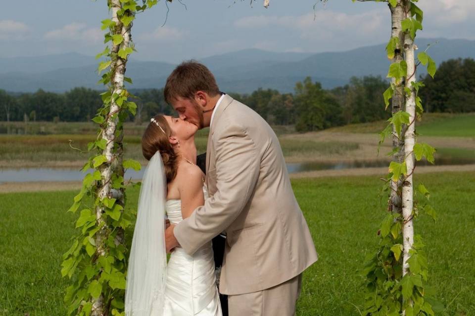 Newlyweds kiss by the field