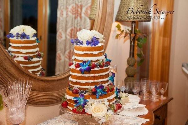Naked cake adorned with f10x sugar, fresh fruit, & flowers.  buttercream icing between the layers.