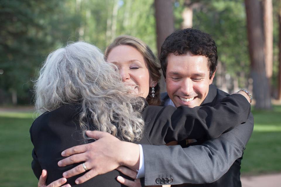 Newlyweds hugging the officiant