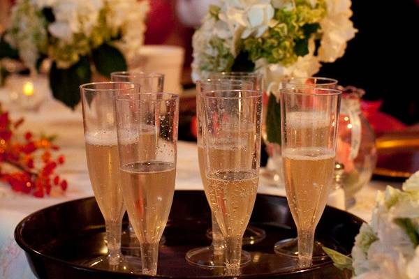 Champagne flutes ready for the toast with bridesmaids' bouquets in the background.