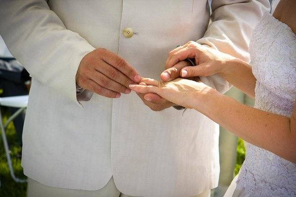 The groom places the ring on the finger of his bride at this beach wedding in Florida.