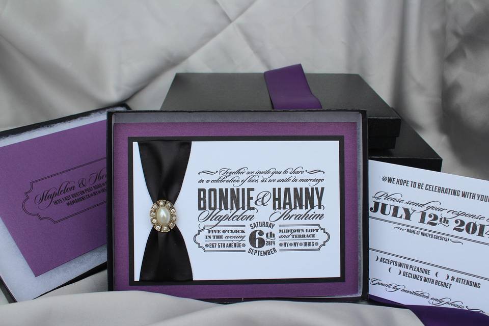 Letterpressed and boxed wedding invitations with ribbon and a brooch