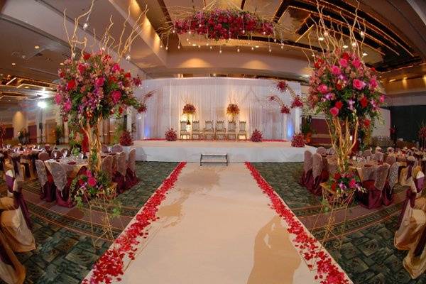 Breathtaking affair for 660 guest with thousands of red and fuchsia roses accented with Bombay Orchids.  The arches were custom made with gold painted curly willow branches votives hung from crystal garland.