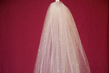 This is our traditional veil it is two tiers, square cut with white shimmer tulle. It is trimmed with a beautiful tulle/pearl twisted edgeing and accented with silver glass beads and rhinestones. This veil is a ballet length