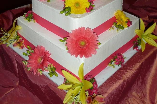Square wedding cake with flowers and pink ribbons
