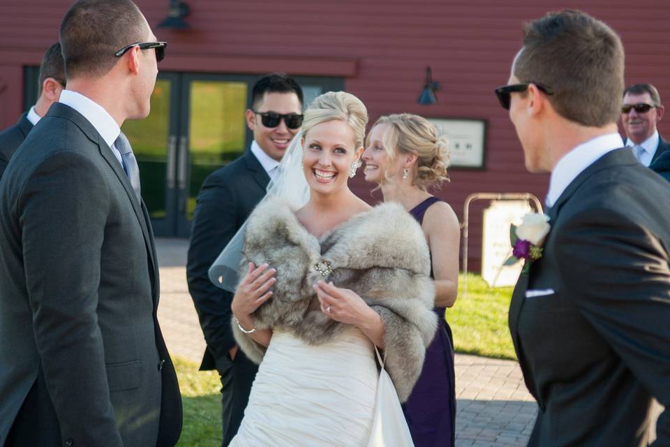 Bride in faux fur wrap surrounded by admiring groomsmen at the Barn at Gibbet Hill. ©2018 Fort Point Media LLC, All Rights Reserved.