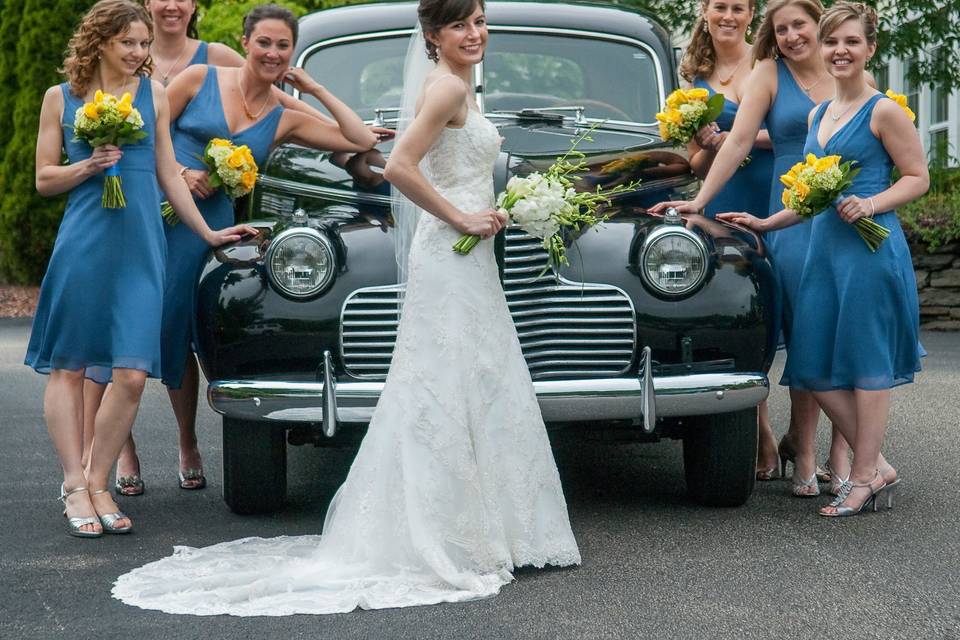 Bride and bridesmaids pose with antique Buick Super at Log Cabin Wedding in Holyoke. ©2018 Fort Point Media LLC, All Rights Reserved.