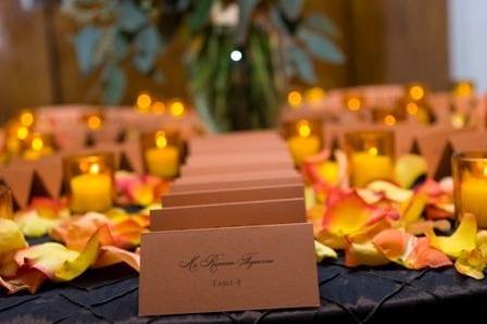 Spice escort cards, circus rose petals and amber votives.