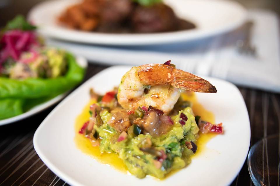 Shrimp resting on a bed of guacamole