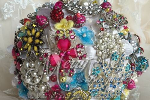 This is a very colorful brooch bouquet that is 7 inches around and is adorned with yellow, fuchsia and turquoise accents and brooches. this can be duplicated almost exactly