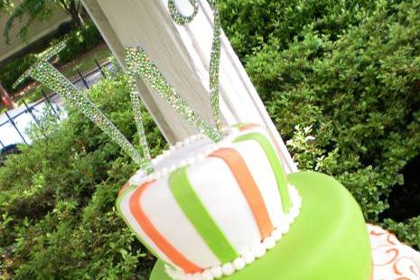 3 tiered fondant covered cake decorated with citrusy colors and topped with jeweled monogram topper.