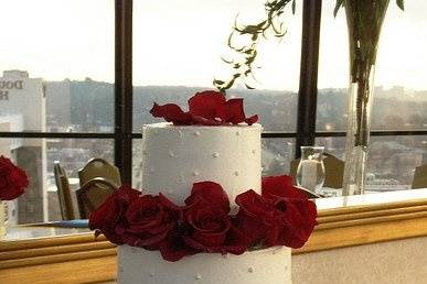3 tiers buttercream covered cake separated by beautiful red roses