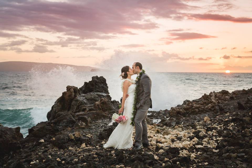 Photo of bride and groom at sunset with the waves crashing in the distance taken by Maui wedding photographers Karma Hill Photography.