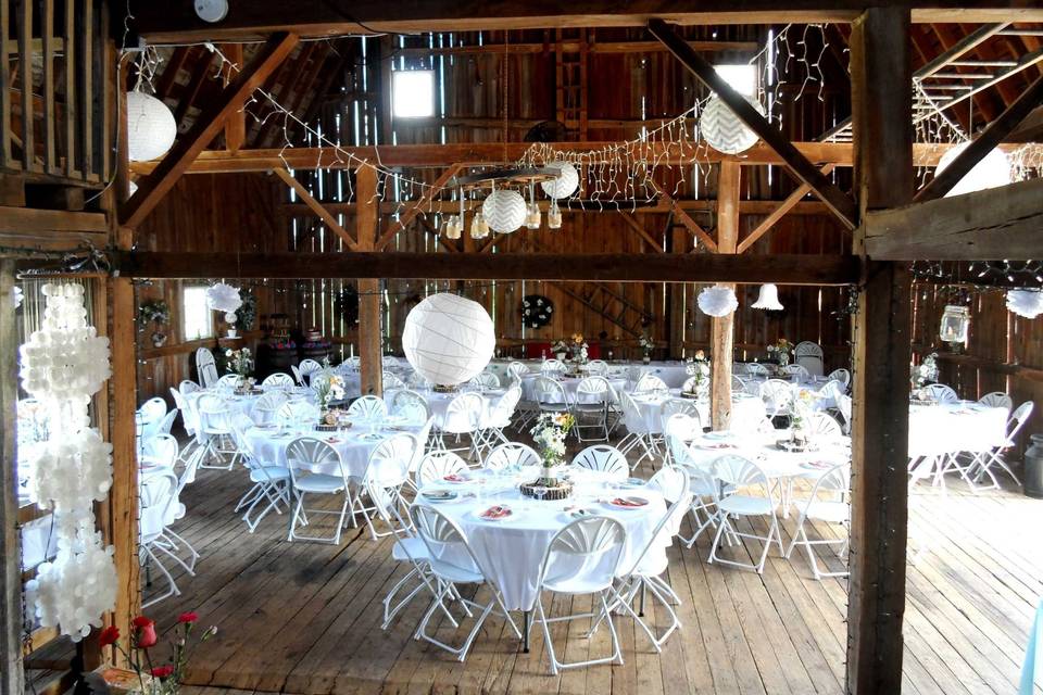Round white tables and white fan-back chairs are provided by The Little Red Barn of Nunica!
