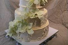 A strikingly tall wedding cake frosted in our rich buttercream. Each tier is then piped in a different pattern. The orchids are a mix of silk and hand crafted gum paste replicas.