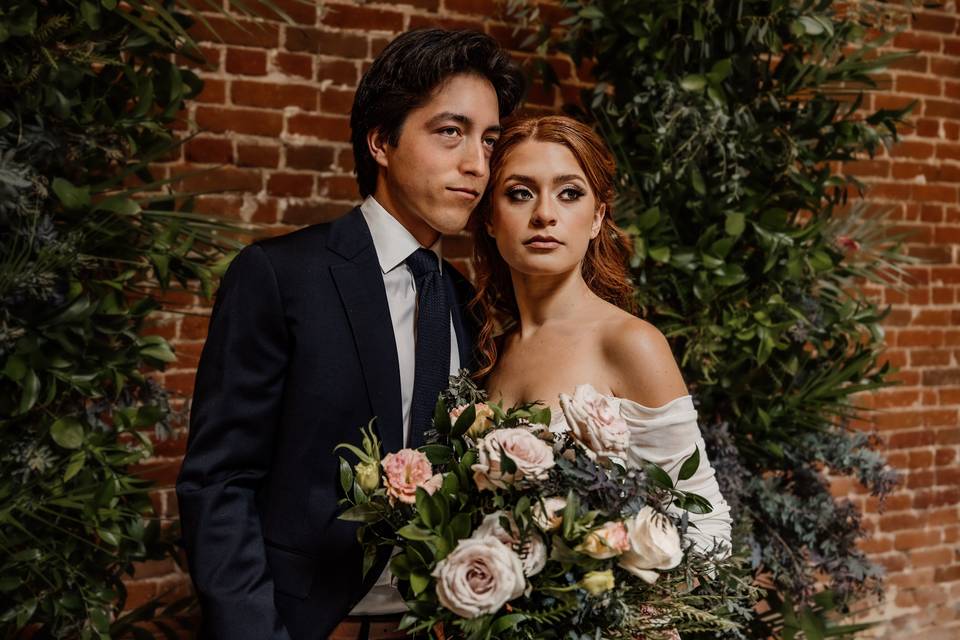 Newlyweds by a greenery wall