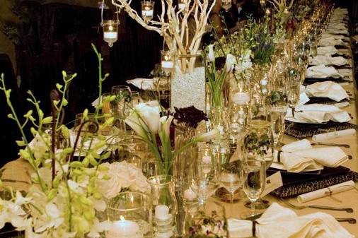 Table scape includes various vases each filled with a different flower.  Very dramatic look using mirrors, candles and branches.  Photography by Nanci Kerby
