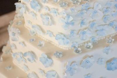 Hundreds of tiny blue sugar blossoms lightly covering buttercream tiers....