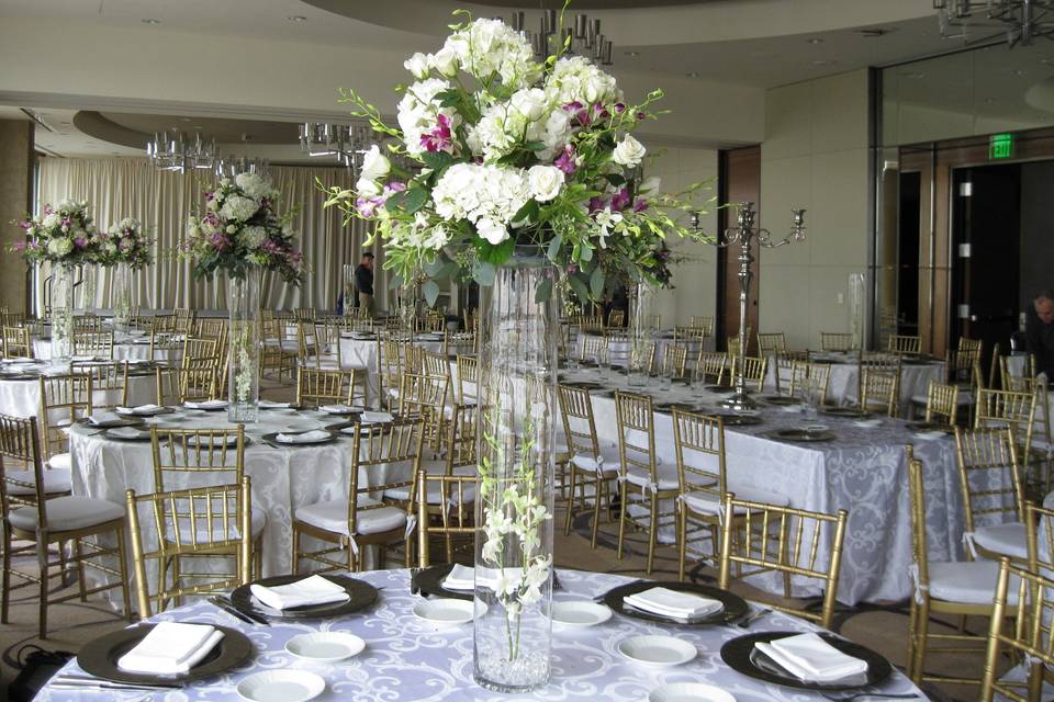 High-top centerpiece cascading with flowers, even the bottom is decorated with a stem of orchids.