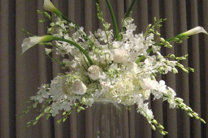 All white dramatic high top centerpieces with orchids suspended with jewels in the bottom of the vases.