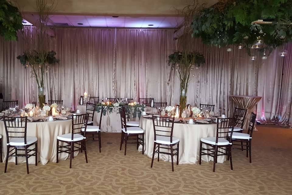 920 Events providing mahogany chiavari chairs, full length custom table linens, full fabric draping around the room, custom designed greens with glass terrariums.