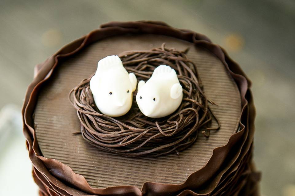 Little hand crafted fondant birds on top of a dark chocolate ruffle cake