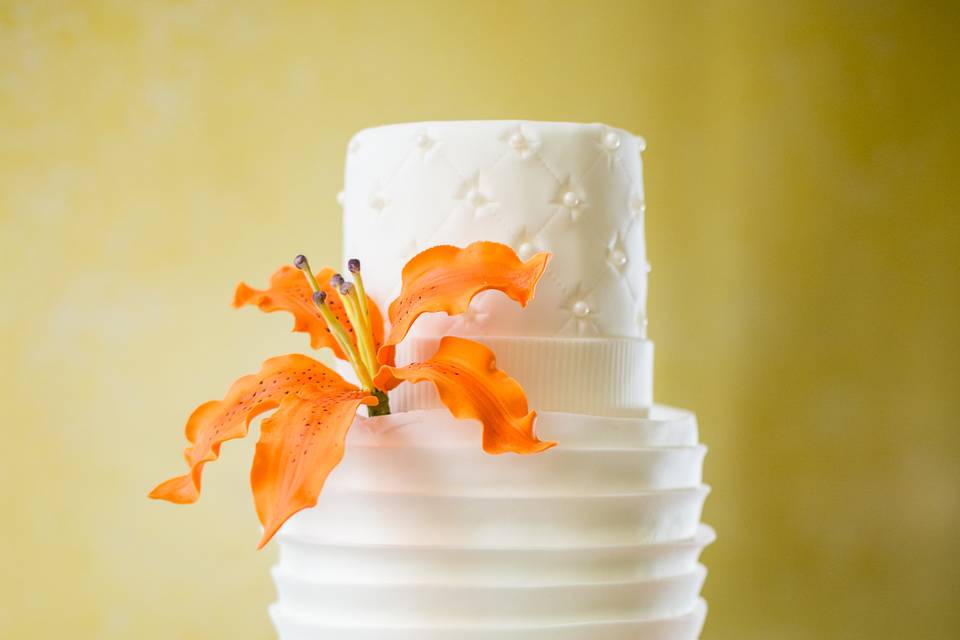 White on white cake with orange hand crafted gum paste lilies